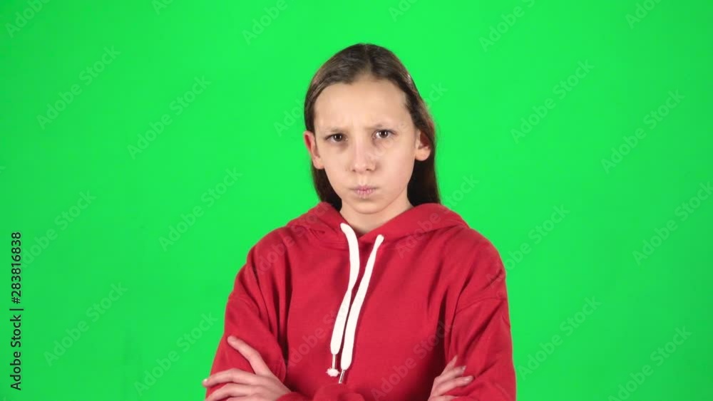 Cute girl is angry and unsatisfied standing with hands at her hips on green background. Slow motion Cute girl is angry and unsatisfied standing with hands at her hips on green background. Slow motion