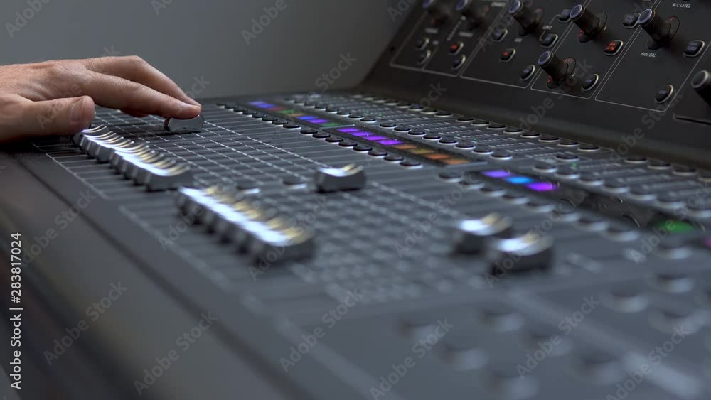 Man works on a professional electronic audio mixer. A control panel for tuning sound channels Man works on a professional electronic audio mixer. A control panel for tuning sound channels
