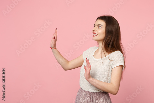 Amazed young woman in casual light clothes posing isolated on pink background. People lifestyle concept. Mock up copy space. Touch something like push click on button point at floating virtual screen.