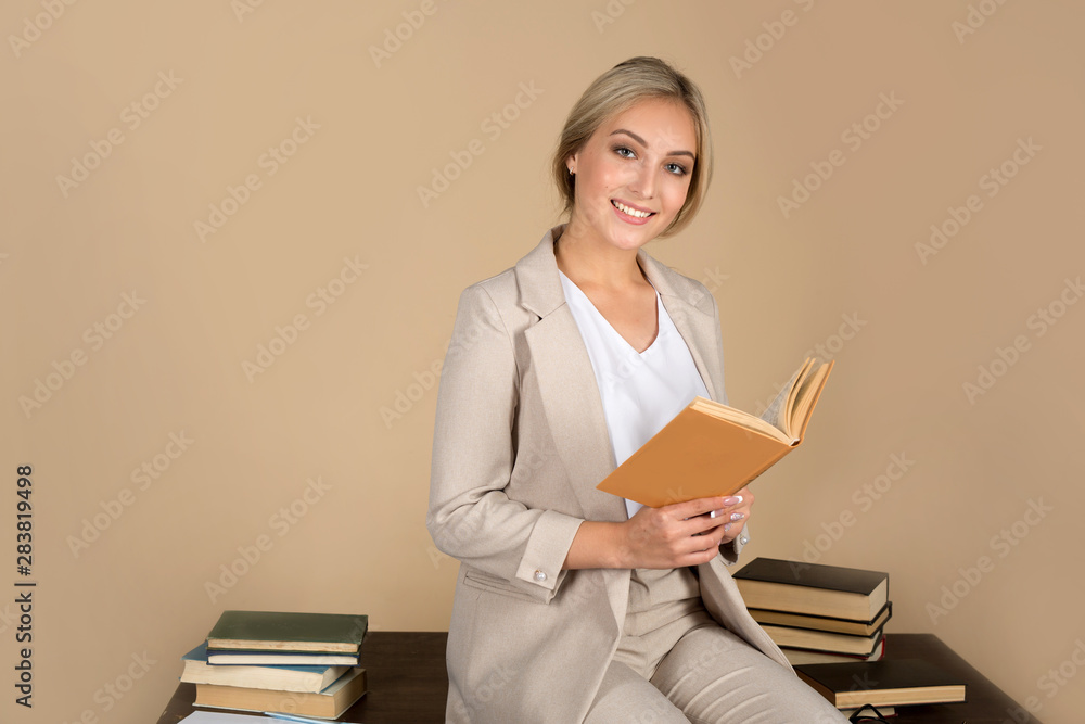 Fototapeta premium beautiful young woman in a suit sitting on a table with a book in her hand