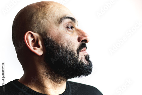 Close-up portrait, profile, of a bearded bald man with white background