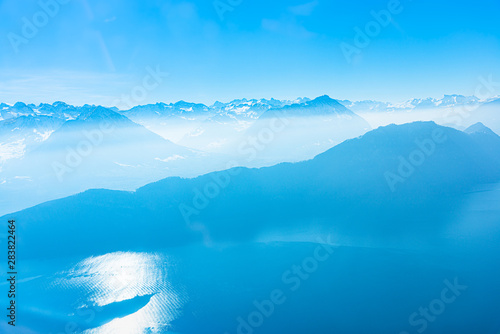 Majestic unique misty blue alpine skyline aerial view panorama of Lake Lucerne, iced Swiss Alps and blue sky, taken from inside a cable lift cabin at mount Rigi Switzerland.