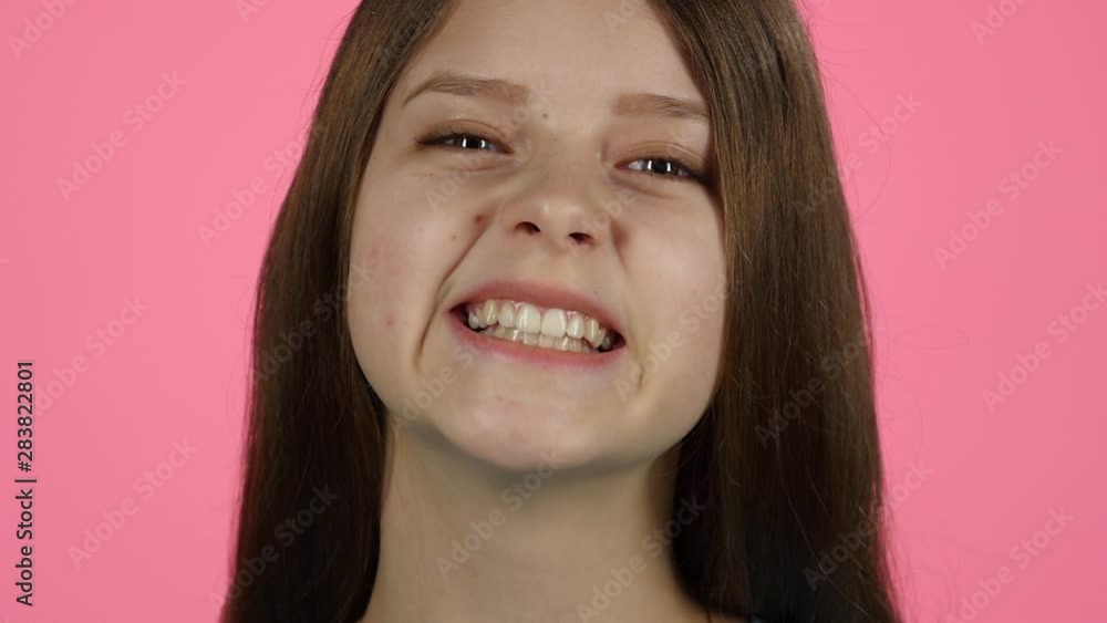 Young female is laughing in the studio on pink background.Slow motion. Close up Young female is laughing in the studio on pink background.Slow motion. Close up