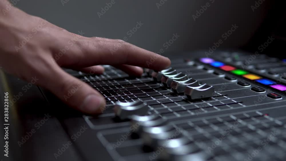 Man works on a professional electronic audio mixer. A control panel for tuning sound channels Man works on a professional electronic audio mixer. A control panel for tuning sound channels