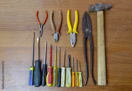 set of repair and craft tools on wooden background. Top view of pliers, hammer, screwdrivers.
