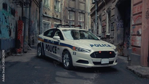 Drone zooming view of white police patrol car standing in tight old street roadblocking the exit. Police on duty. Crime accident in city center. photo