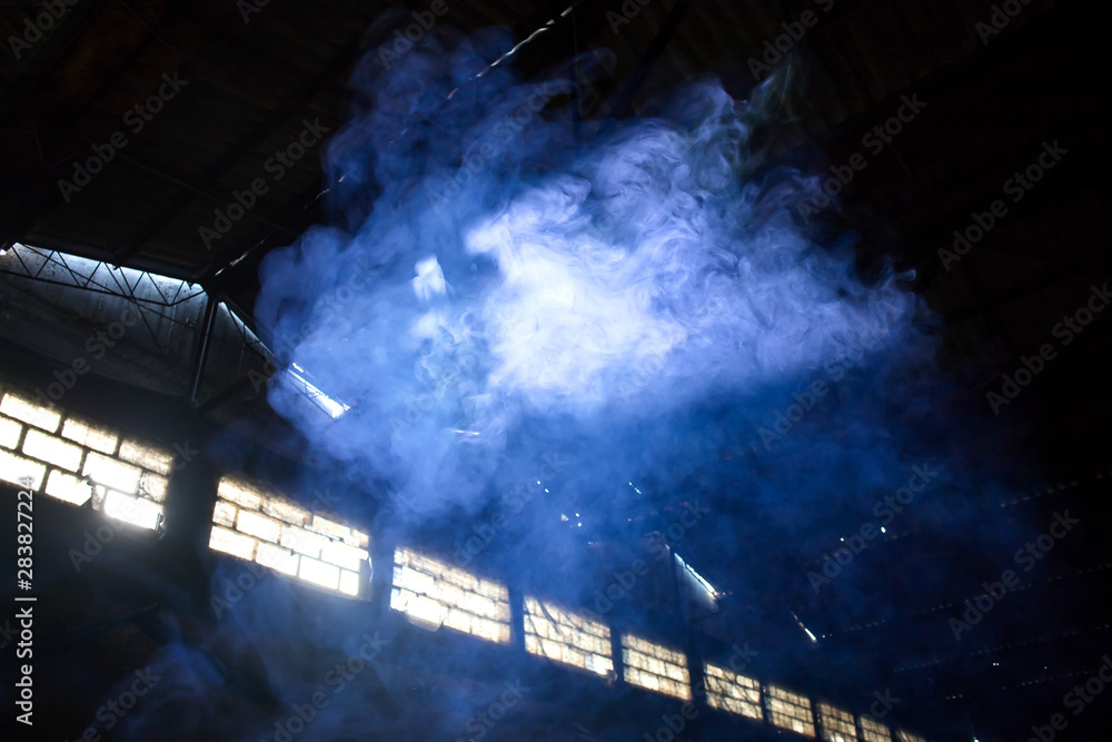 blue smoke bomb exploding cloud in deserted empty hangar Stock Photo