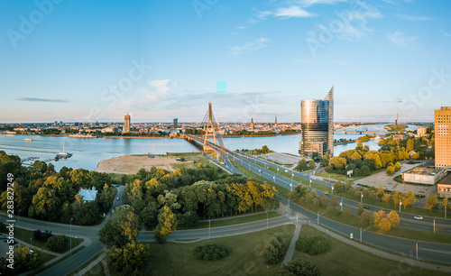 Panoramic, aerial view over Riga city. Modern buildings, roads, and other infrastructure. Cable bridge leading to iconic old town panorama in vivid sunset colors.  © Viesturs