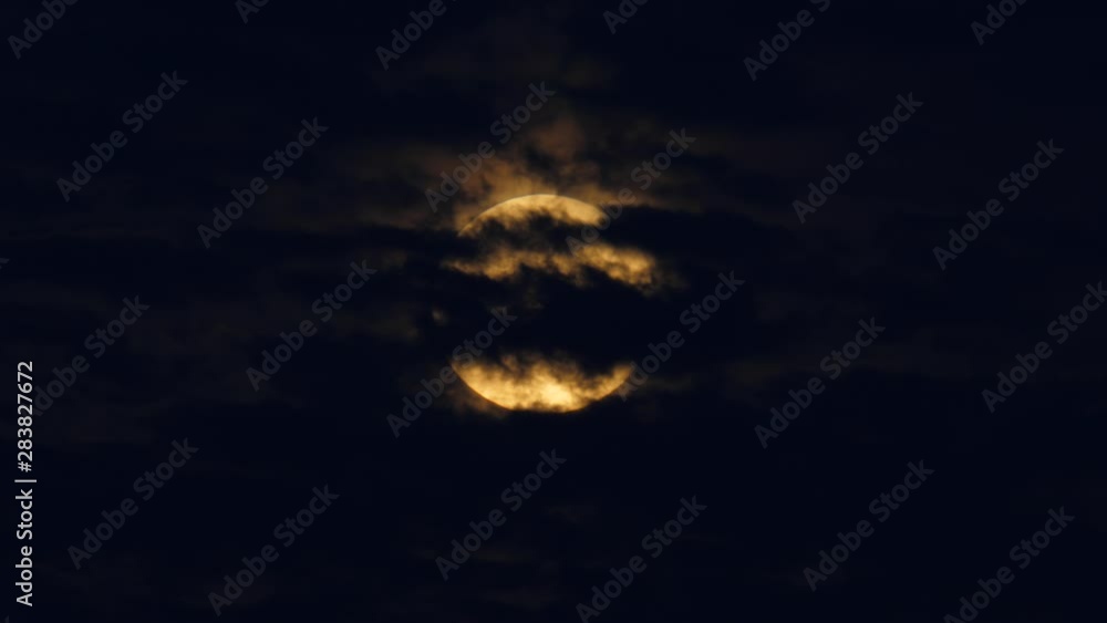 Disc of full moon move across sky, covered by dark clouds sliding fast in opposite direction. Real time lapse shot, telephoto lens used Disc of full moon move across sky, covered by dark clouds sliding fast in opposite direction. Real time lapse shot, telephoto lens used