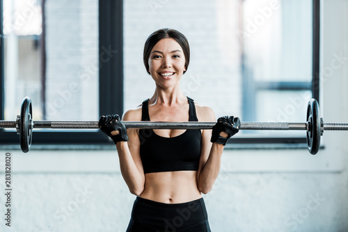 cheerful woman working out with barbell in gym