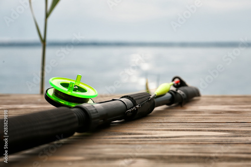 Modern fishing rod on pier near river, closeup