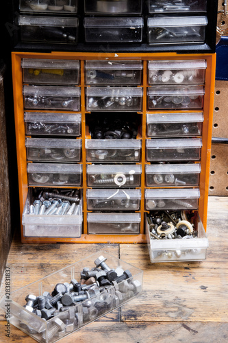 Plastic parts storage with drawers and filled with nuts and bolts; small hardware organized into drawers on a work bench photo