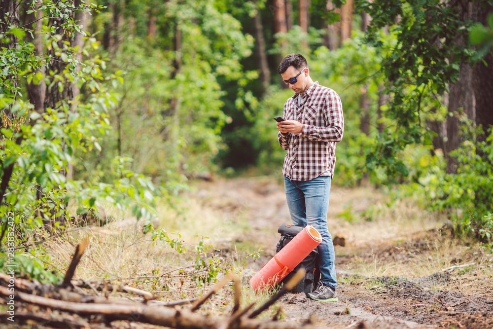 Hipster young man with backpack using smart phone on beautiful nature.Travel concept. Outdoor travel. Travel and explore. Backpacker male Going in forest Gps Route. Portrait hiker using mobile phone Hipster young man with backpack using smart phone on beautiful nature.Travel concept. Outdoor travel. Travel and explore. Backpacker male Going in forest Gps Route. Portrait hiker using mobile phone