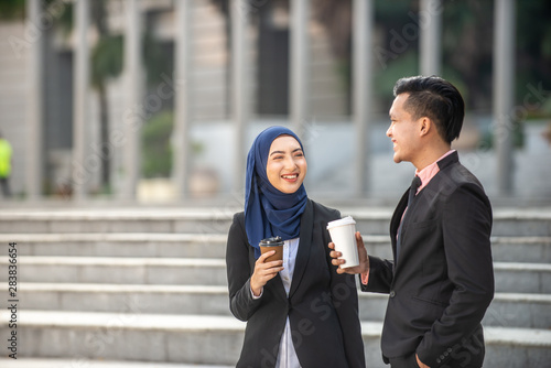 Muslim Businessman and Businesswoman having a conversation during a coffee break. Outdoor scene.