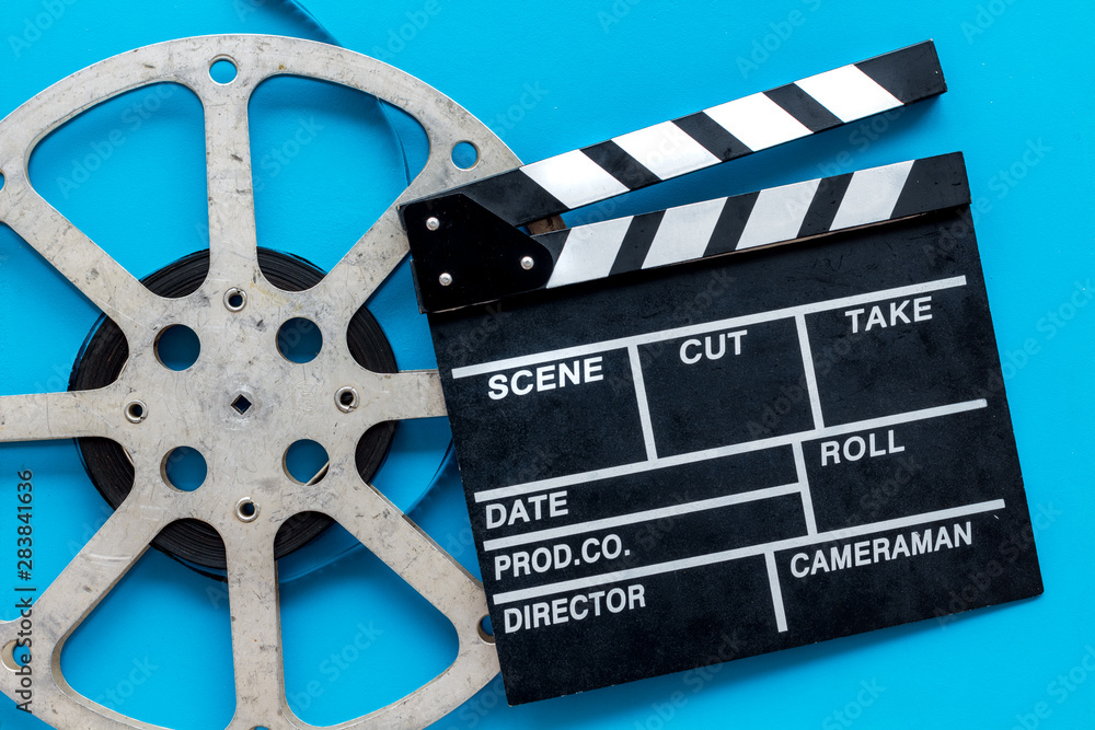 Filmmaker profession with clapperboard and video tape on blue background top view