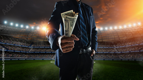Valokuva businessman holding large amount of bills at Soccer stadium in background