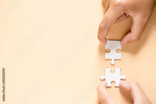 hand connecting two puzzle pieces on table background