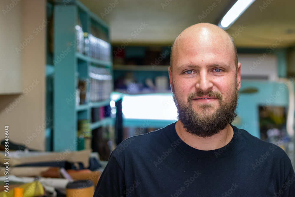 Portrait of a bald mand with beard, shoemaker looking camera at his workshop. Portrait of a bald mand with beard, shoemaker looking camera at his workshop.