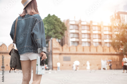 Smiling woman traveler in thapae gate landmark chiangmai thailand with backpack holding world map and camera on holiday, relaxation concept, travel concept photo