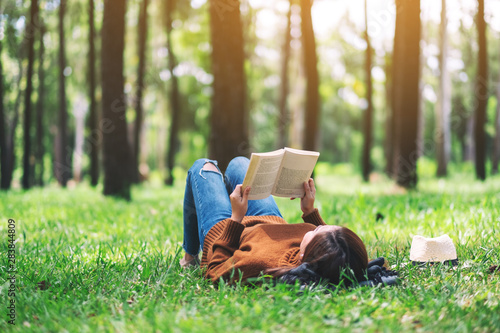 Piękna Azjatycka kobieta kłama książkę w parku i czyta