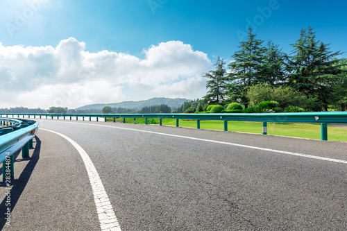 Country asphalt road and green woods with mountain nature landscape in summer