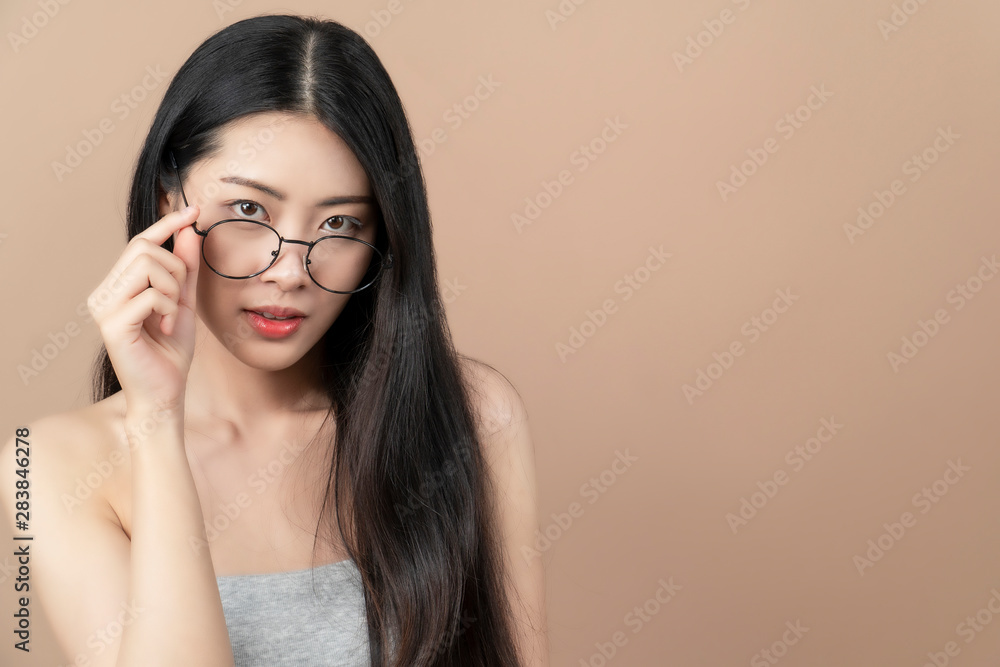 Pretty attractive  Asian woman holding her glasses.Beige background.