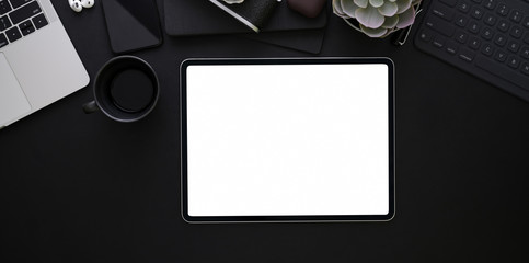 Blank screen tablet on black leather background in dark stylish workplace