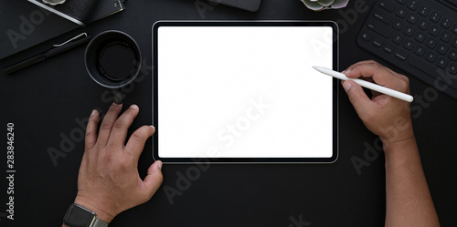 Man drawing on blank screen tablet in dark luxury office