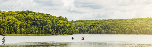  Canada forest park nature with family friends riding in red kayaks canoe boats in water. Beautiful landscape scene at Canadian  lake river area. Web banner header for website.