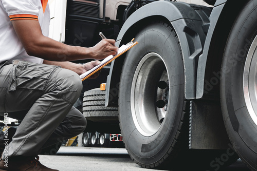 Auto Mechanic is Checking the Truck's Safety Maintenance Checklist. Lorry Fixing. Truck Inspection Safety of Semi Truck Wheels Tires. Auto Service Shop. 	