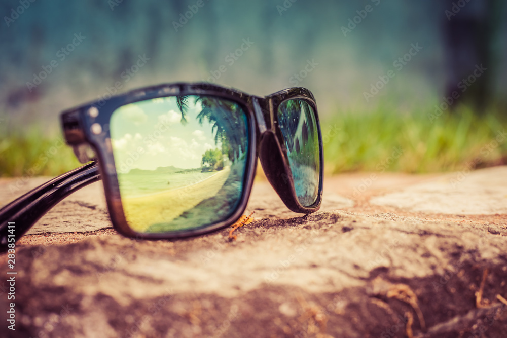 Fashionable sunglasses. Sunglasses with mirrored lenses. Reflection of the beach and tropical palm trees in sunglasses