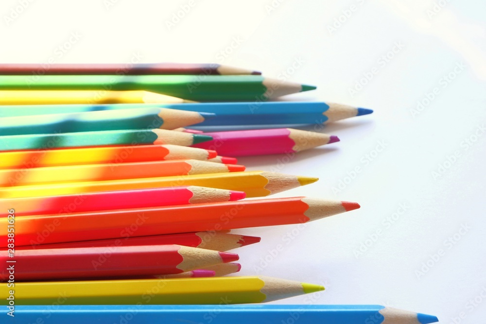 The sun's rays fall on the colored pencils lying on a white background. Color Therapy Concept.Copy space for text, with selective focus. The sun's rays fall on the colored pencils lying on a white background. Color Therapy Concept.Copy space for text, with selective focus.