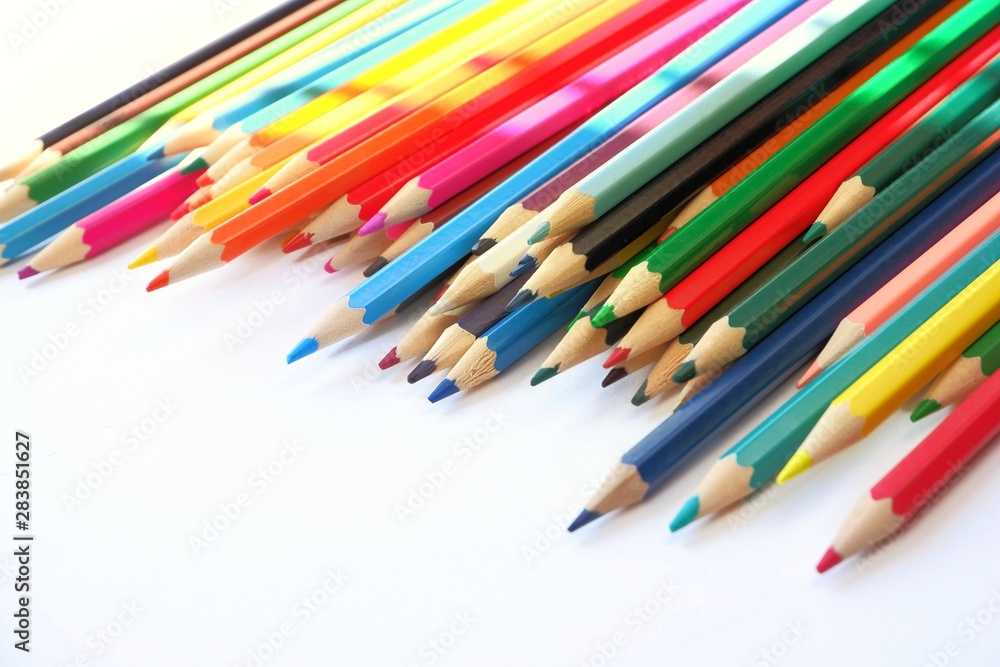 The sun's rays fall on the colored pencils lying on a white background. Color Therapy Concept.Copy space for text, with selective focus. The sun's rays fall on the colored pencils lying on a white background. Color Therapy Concept.Copy space for text, with selective focus.