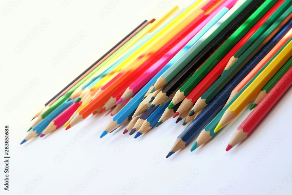 The sun's rays fall on the colored pencils lying on a white background. Color Therapy Concept.Copy space for text, with selective focus.