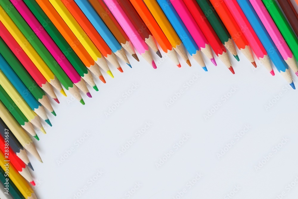 Fototapeta premium Composition semicircle made of mixed colored pencils on a white background.The concept of anti-stress, hobby.With selective focus,copy space for text.