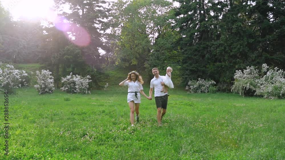 A young woman an a young man run towards camera in the park in slow motion. Love and Happiness. A young woman an a young man run towards camera in the park in slow motion. Love and Happiness.