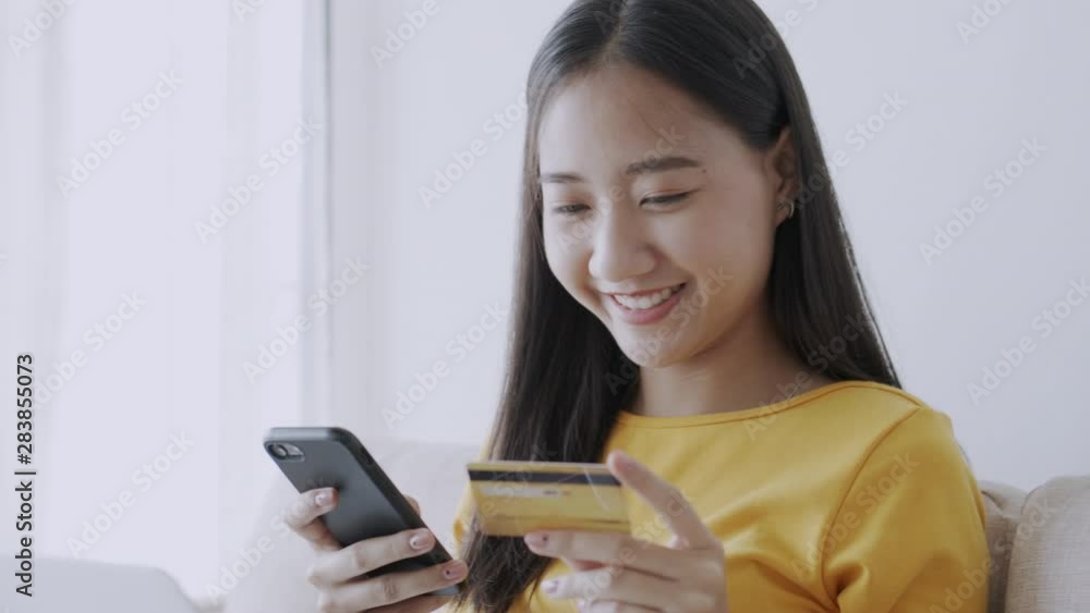 beautiful of Asian women are buying online with a credit card and smile while sitting on the sofa at home. woman are using smart phone and doing online transactions, Past the internet beautiful of Asian women are buying online with a credit card and smile while sitting on the sofa at home. woman are using smart phone and doing online transactions, Past the internet
