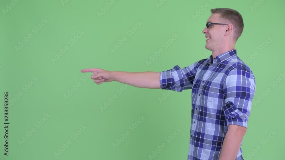 Profile view of happy young hipster man pointing finger Profile view of happy young hipster man pointing finger
