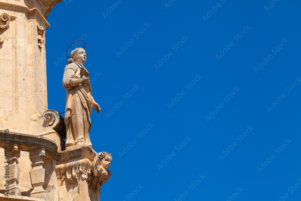 Close up of details of baroque obelisk of Sant'Oronzo in Ostuni, Puglia, Italy. Clean blue sky. Baroque monument in the White city Ostuni.