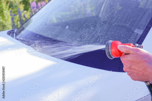 Car warhing. Worker cleaning white car on open air.Cleaning Car Using High Pressure Water. Man washing his car under high pressure water in service.Car cleaning. Wash car with soap. photo