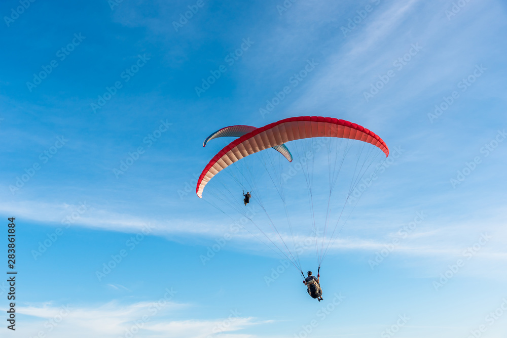 Paragliding Extreme sport, Paraglider flying on the blue sky and white cloud in Summer day at Phuket Sea, Thailand.