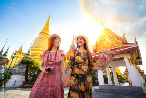 Canvas Print Two asian girlfriends traveling and check location by a map in Grand Palace