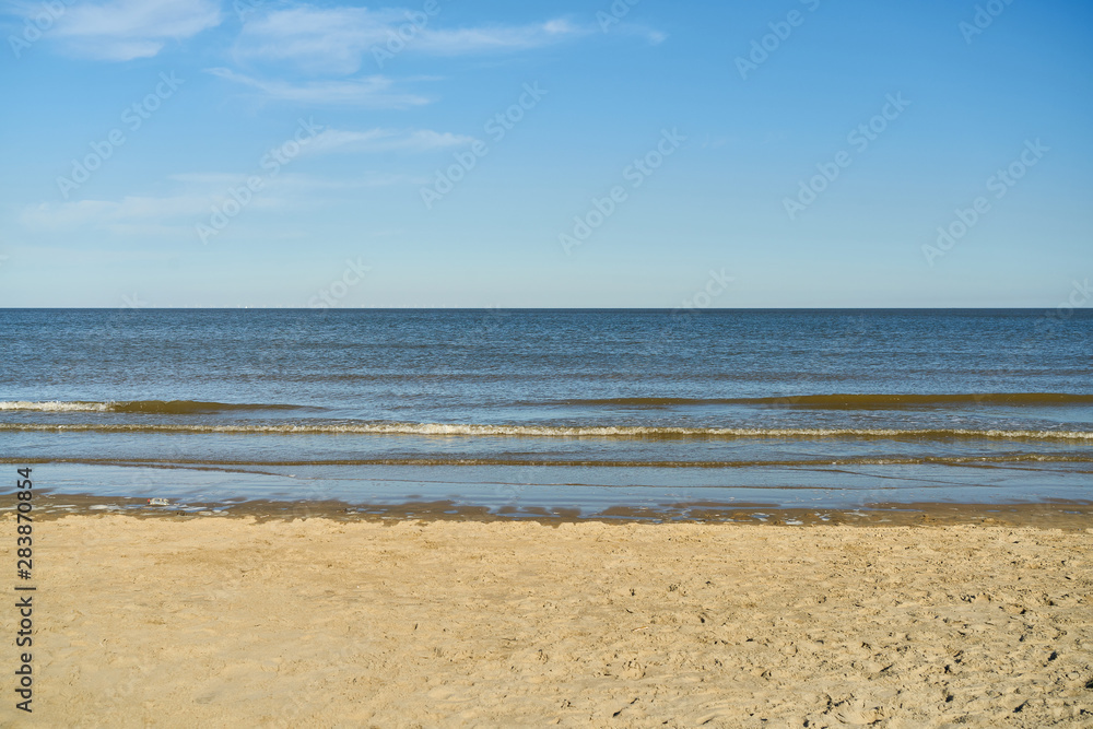 Strand mit Sand vor Meer und Himmel mit Wolken