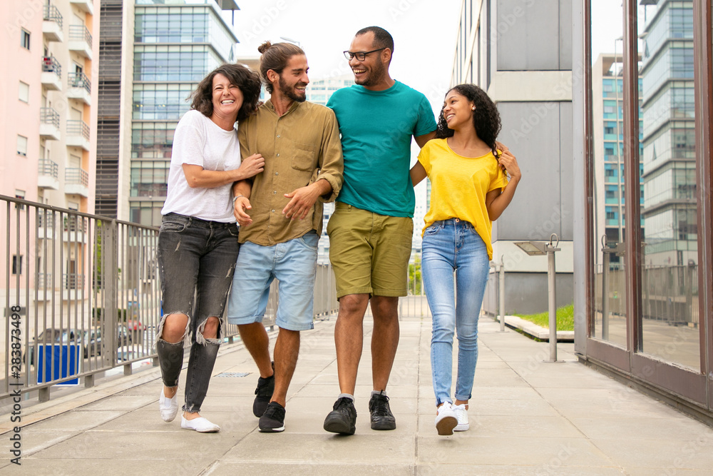 Joyful close friends walking outside. Young mix raced people going down urban street, hugging each other, talking and laughing. Friendship concept Joyful close friends walking outside. Young mix raced people going down urban street, hugging each other, talking and laughing. Friendship concept