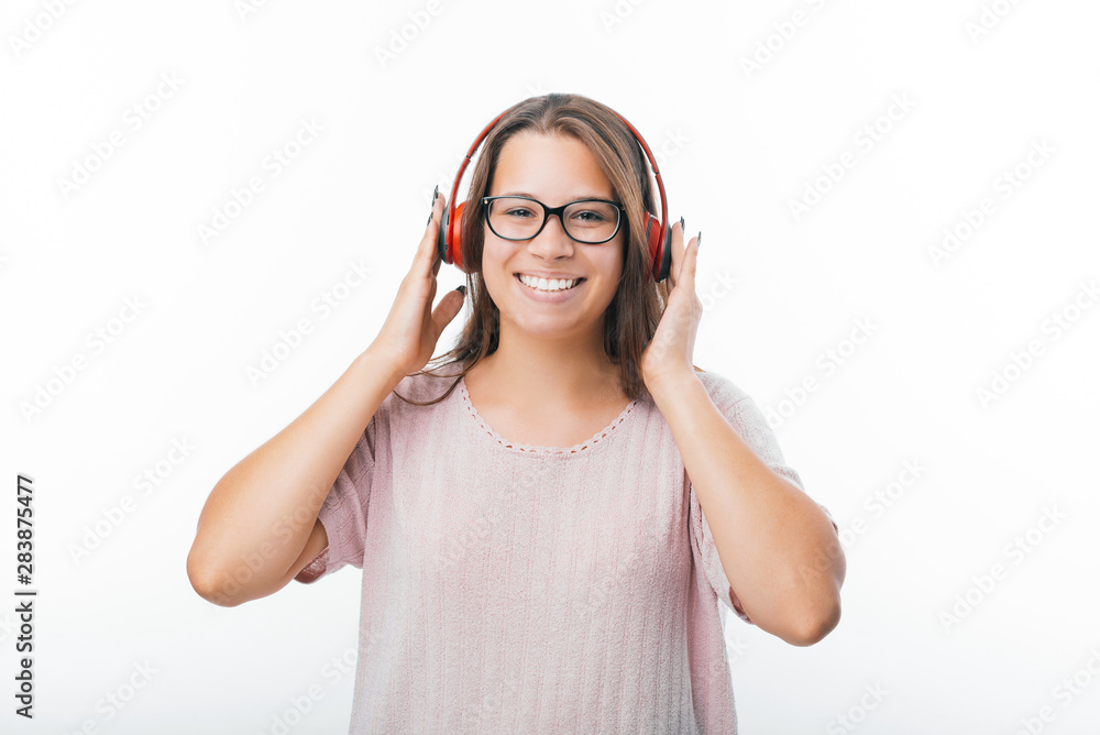 Photo of young woman, using wireless headphones, looking and smiling at camera over white background Photo of young woman, using wireless headphones, looking and smiling at camera over white background
