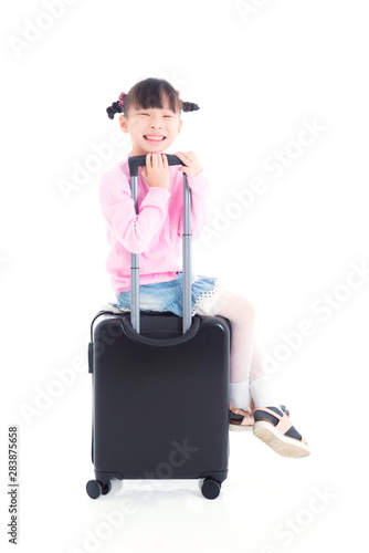 Little asian girl sitting on wheel suitcase and smiles over white background