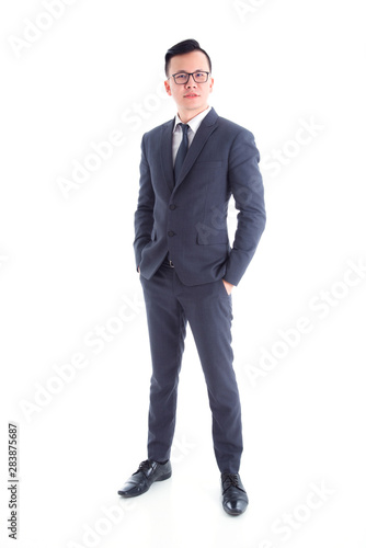 Full length of handsome asian businessman wearing suit standing and smiling isolated over white background
