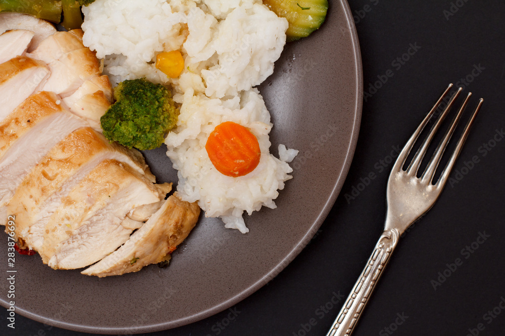 Baked chicken breasts or fillet on plate with rice and vegetables on plate. Baked chicken breasts or fillet on plate with rice and vegetables on plate.