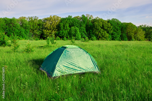 Touristic tent on grass field mountains valley. Nature hiking.