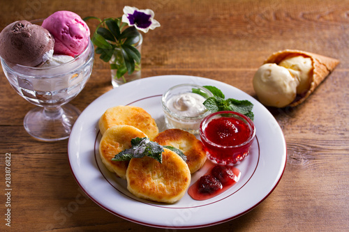 Cottage cheese pancakes. Syrniki with fresh mint, sour cream and strawberry jam, ice cream - dessert concept